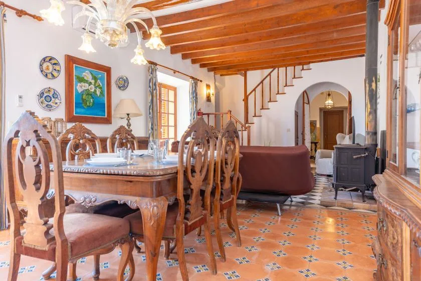 A dining room with a large wooden table, patterned tile floor, and staircase.
