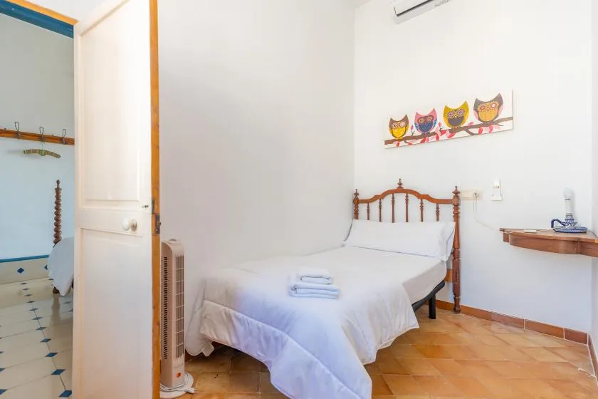 A bedroom with a wooden bed, white bedding, and colorful owl decorations on the wall.