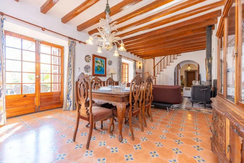 A dining area with a wooden table and chairs beneath exposed ceiling beams.