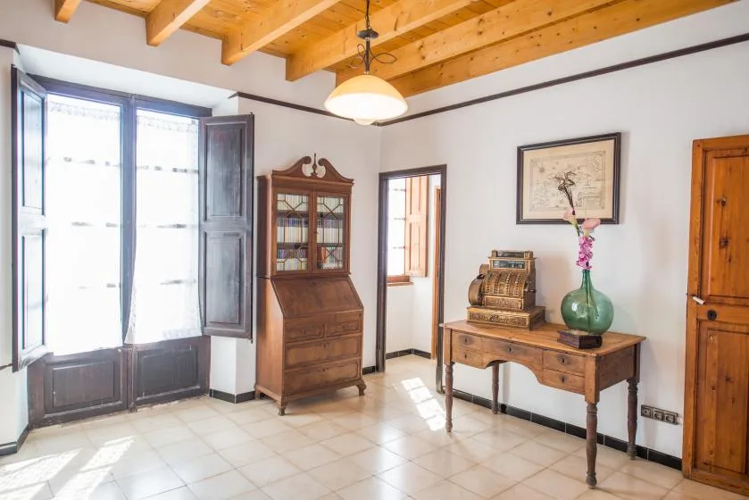 A bright room with a large window, wooden furniture, and exposed ceiling beams.