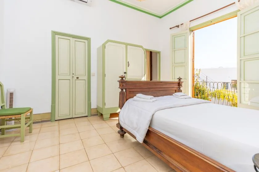 A bedroom with a bed, wooden headboard, and open window.