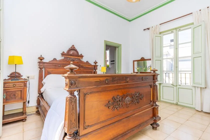 A bedroom with an ornate wooden bed and tall windows.