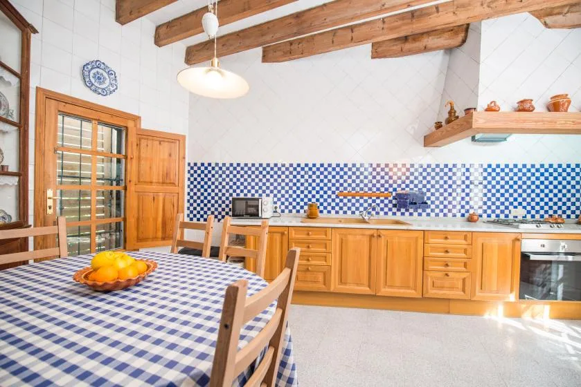 A rustic kitchen with wooden cabinets and a blue-and-white tiled backsplash.