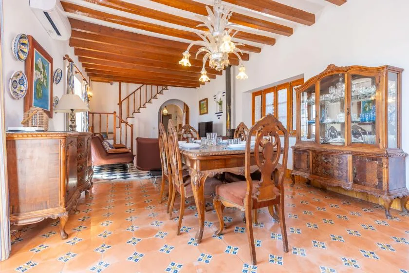 A dining room with a wooden table and chairs beneath exposed ceiling beams.