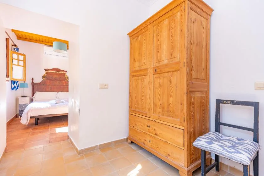 A bedroom with a large wooden wardrobe and a bed visible through the doorway.