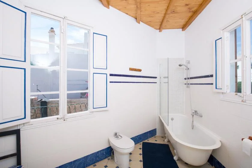 A bright bathroom with a bathtub, shower, and large windows.