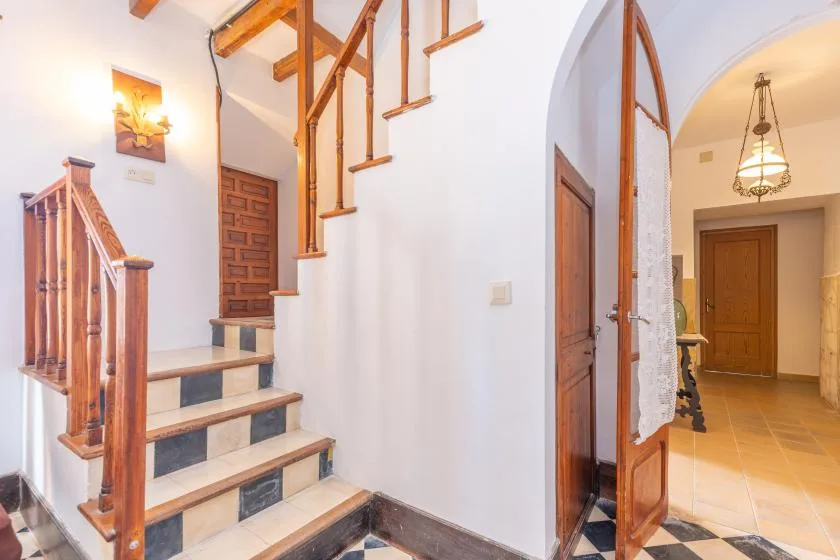 An interior hallway with a staircase and an open doorway leading to another room.