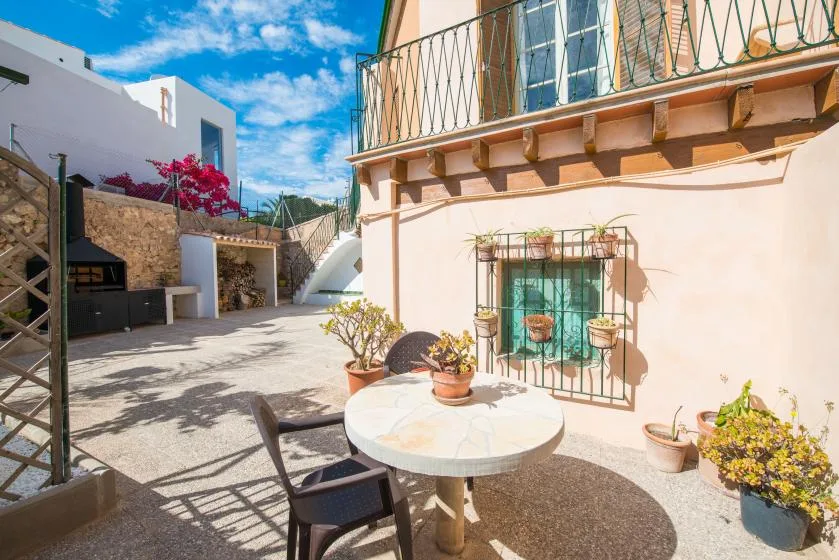 An outdoor patio with a round table and chairs beside a peach-colored building.