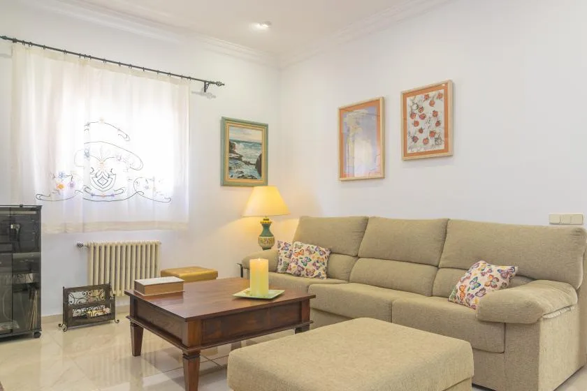 A living room with beige seating, a coffee table, and framed artwork.