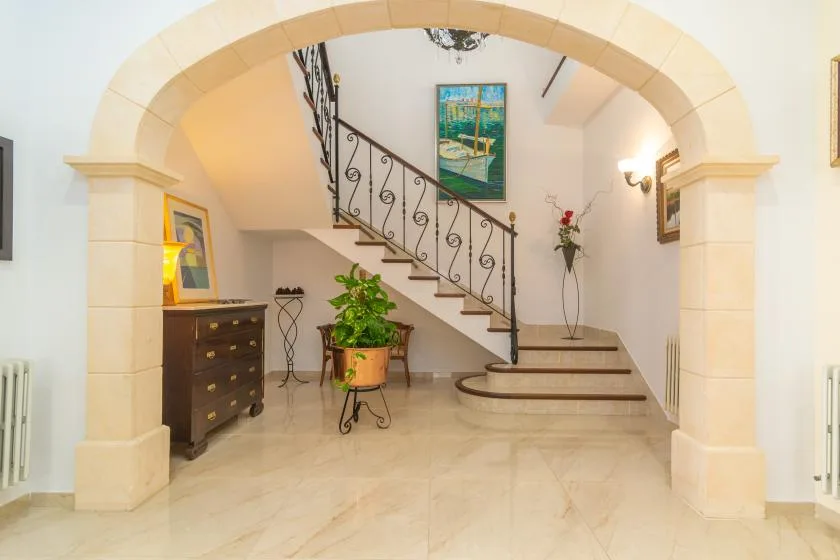 An arched interior entry opens onto a staircase with decorative metal railing.