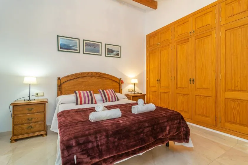A bedroom with a double bed, bedside tables, and wooden wardrobes.
