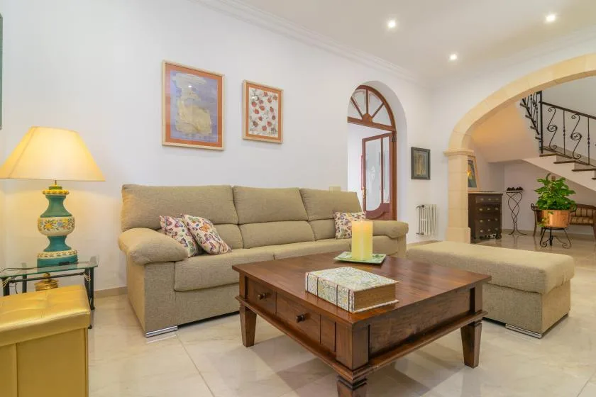 A living room with a sectional sofa, wooden coffee table, and framed wall art.
