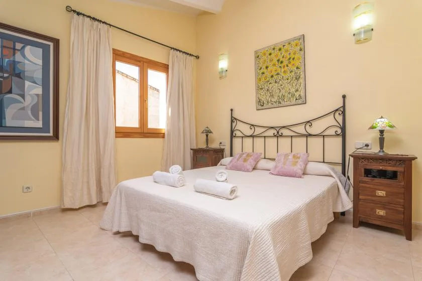 A bedroom with a double bed, bedside tables, and a window with curtains.
