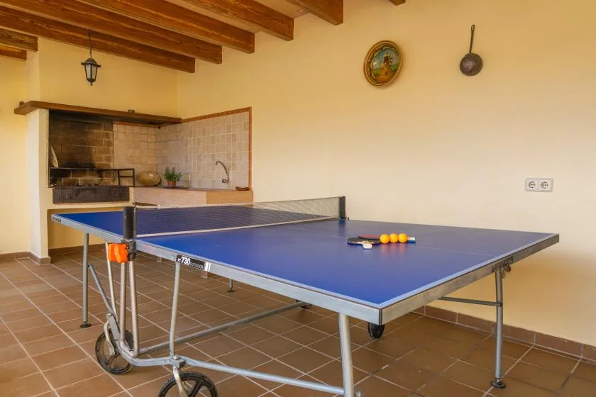 A table tennis table fills a tiled room with exposed wooden ceiling beams.