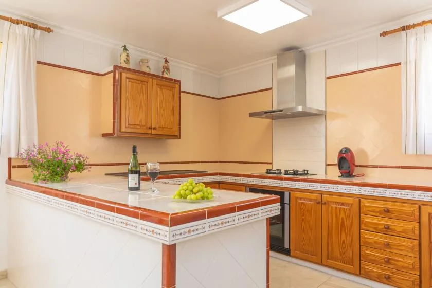 A bright kitchen with wooden cabinets and a tiled island.