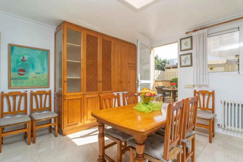 A dining room with a wooden table, chairs, and a large cabinet.
