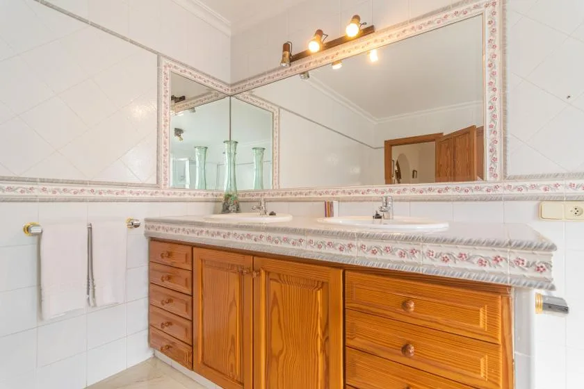 A bathroom vanity with a wide mirror and wooden cabinets.