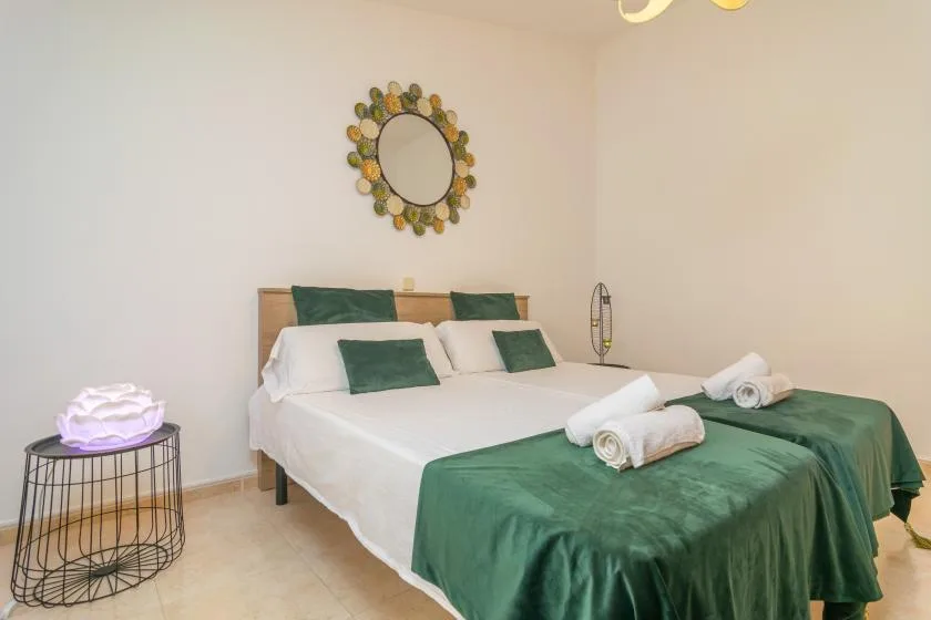 A bedroom with a neatly made bed dressed in white and green linens.