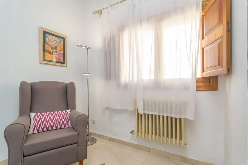 A bright sitting area with an armchair beside a curtained window.