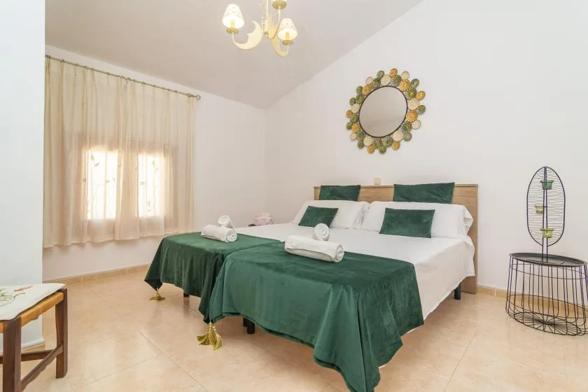 A bedroom with two beds dressed in white and green linens.