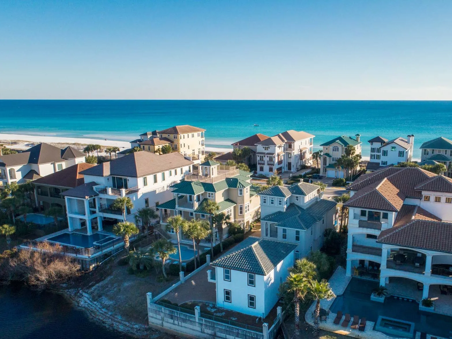 Coastal neighborhood of houses beside a sandy beach and the ocean.