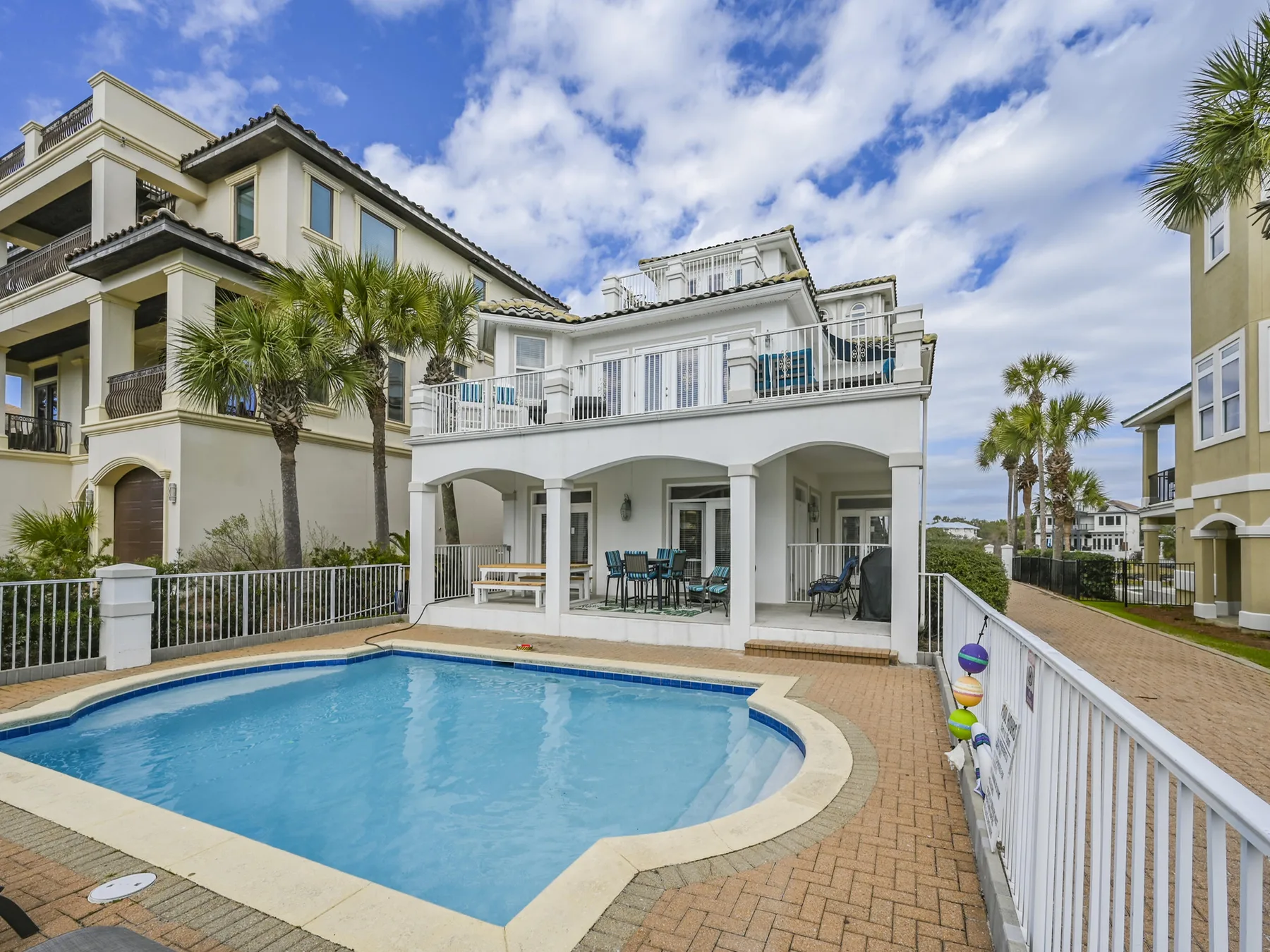 A courtyard pool sits beside a white multi-story building with balconies.