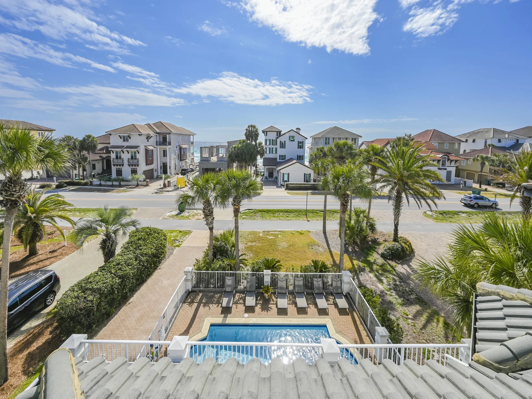 A residential street with palm trees and a swimming pool in the foreground.