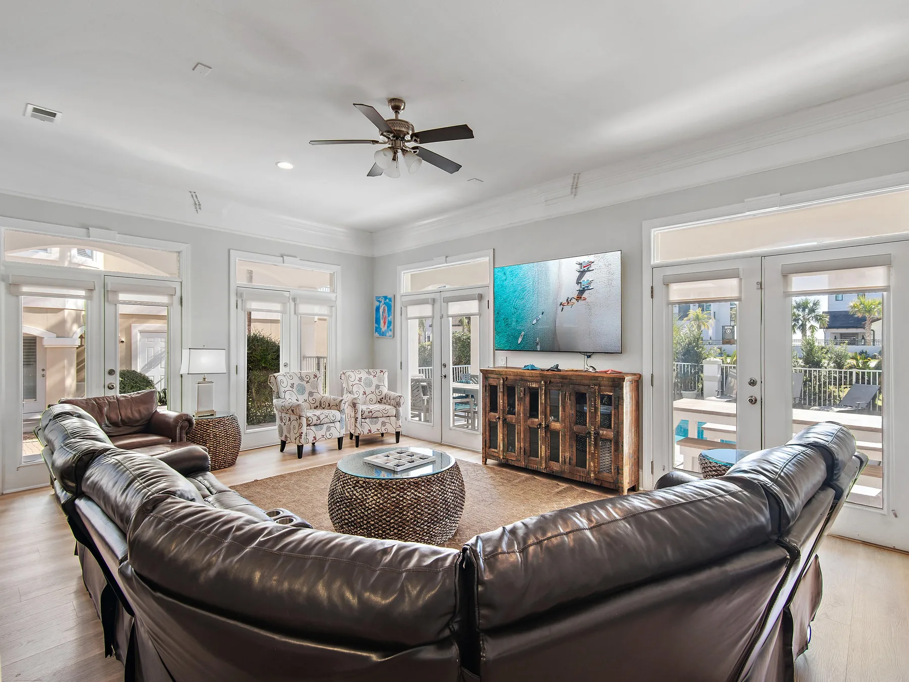 A bright living room with seating arranged around a coffee table and television.