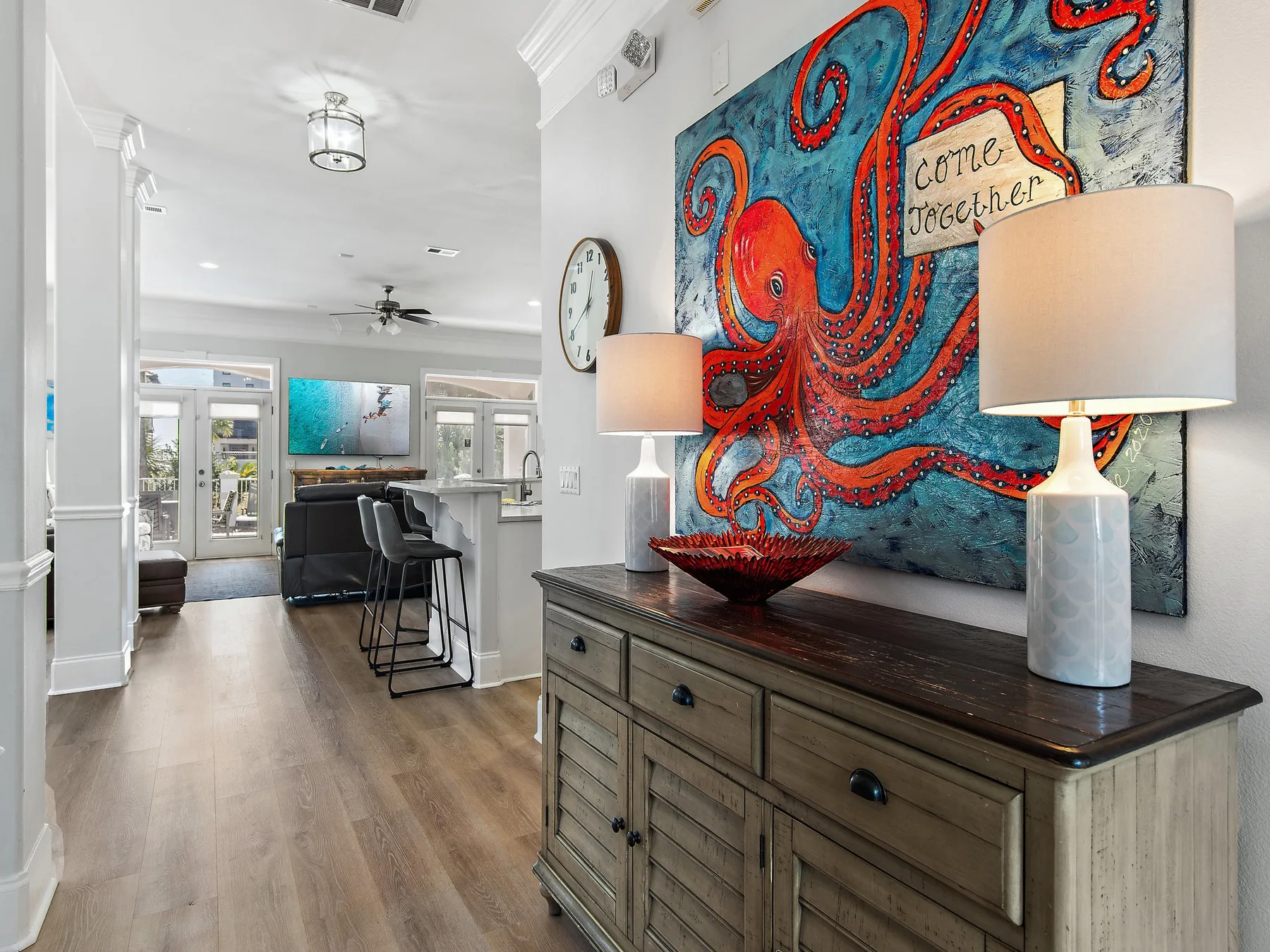 A bright open-plan living area features a kitchen counter and colorful octopus artwork.