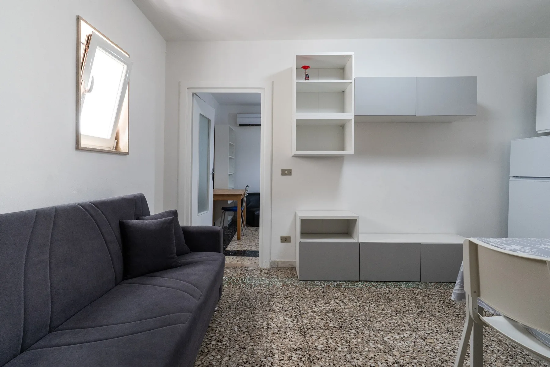 A bright living area with dark seating, pale cabinets, and a doorway.