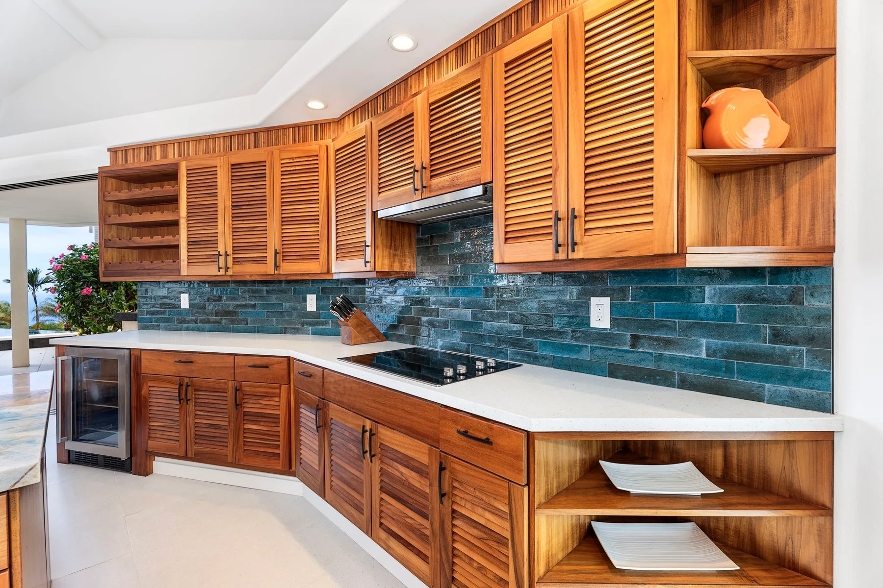 Una cocina con gabinetes de madera, un salpicadero de azulejos verde azulado y encimeras claras.
