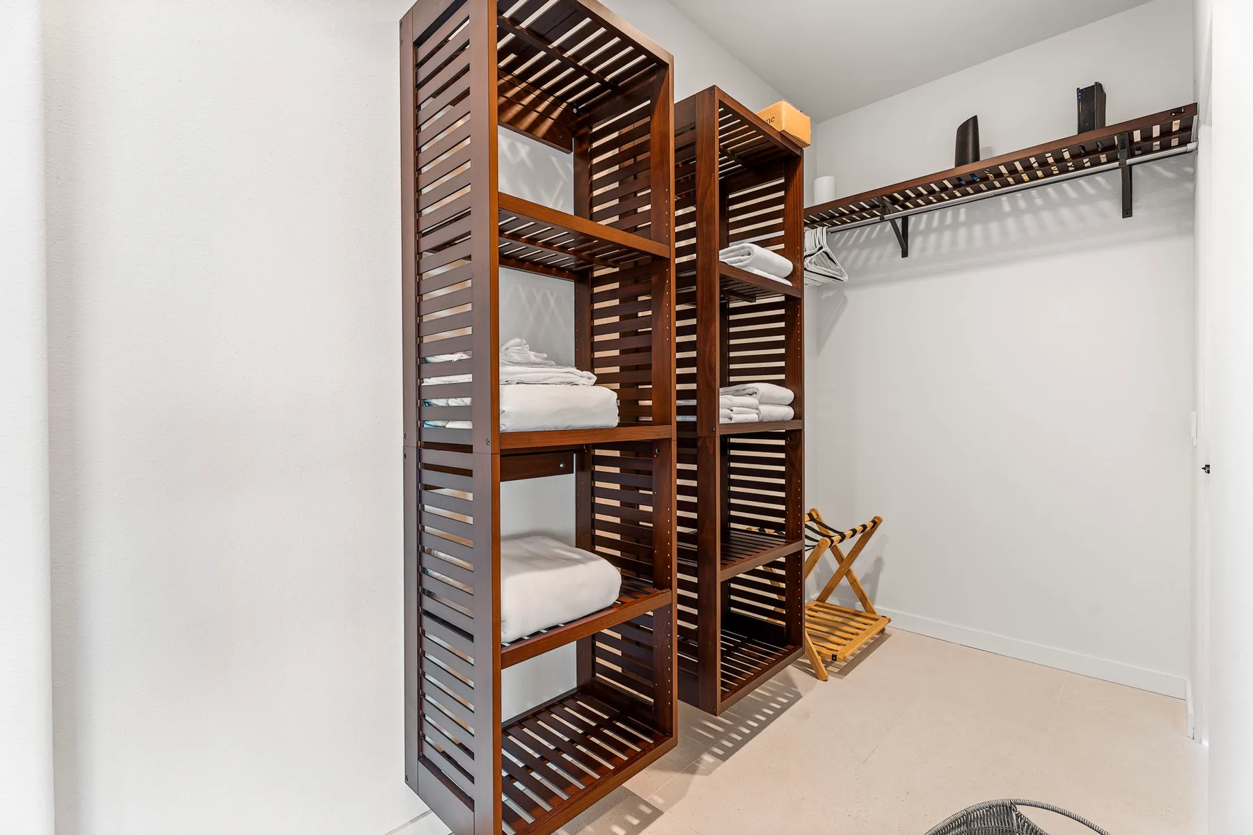 Un vestidor con estantes abiertos, ropa de cama doblada y una barra para colgar.