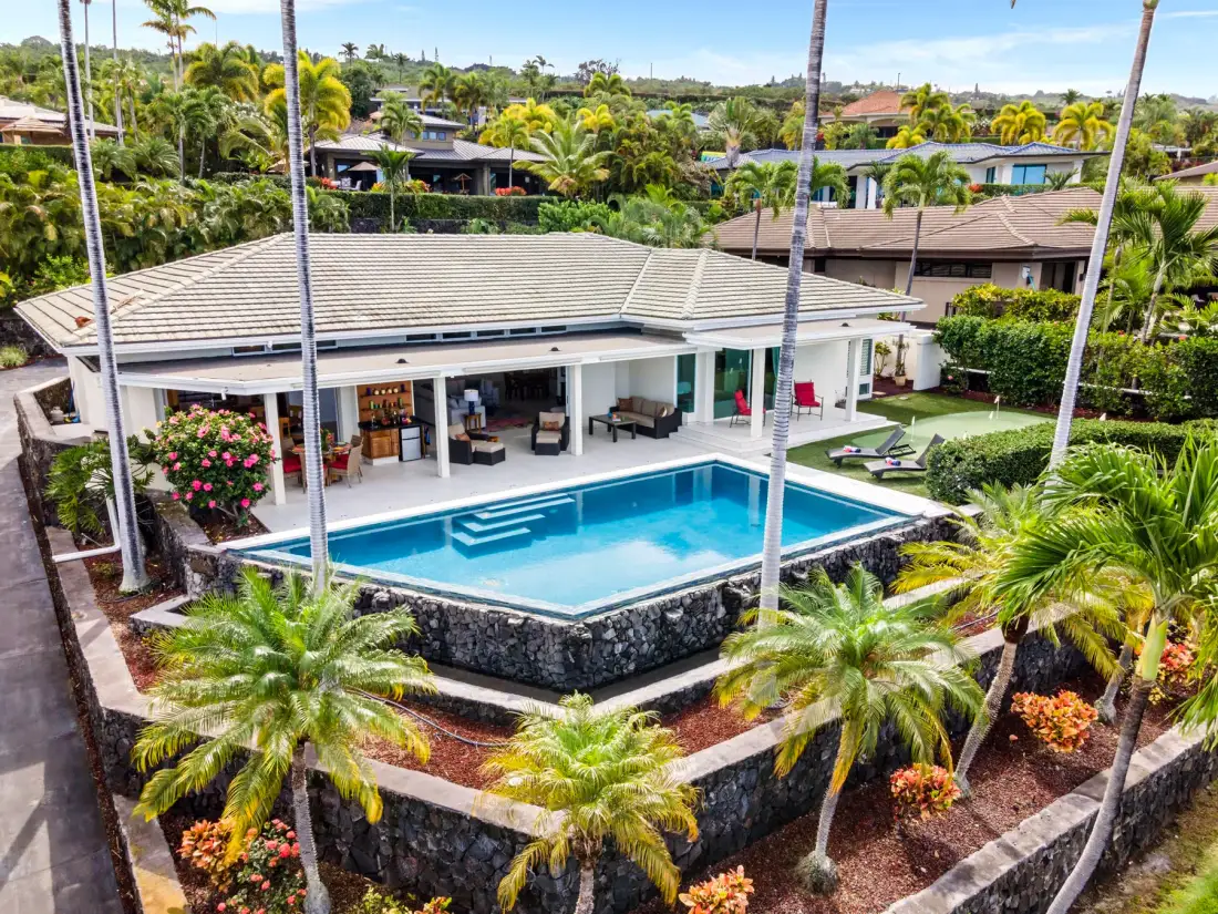 Vista aérea de una casa con piscina rodeada de vegetación tropical.