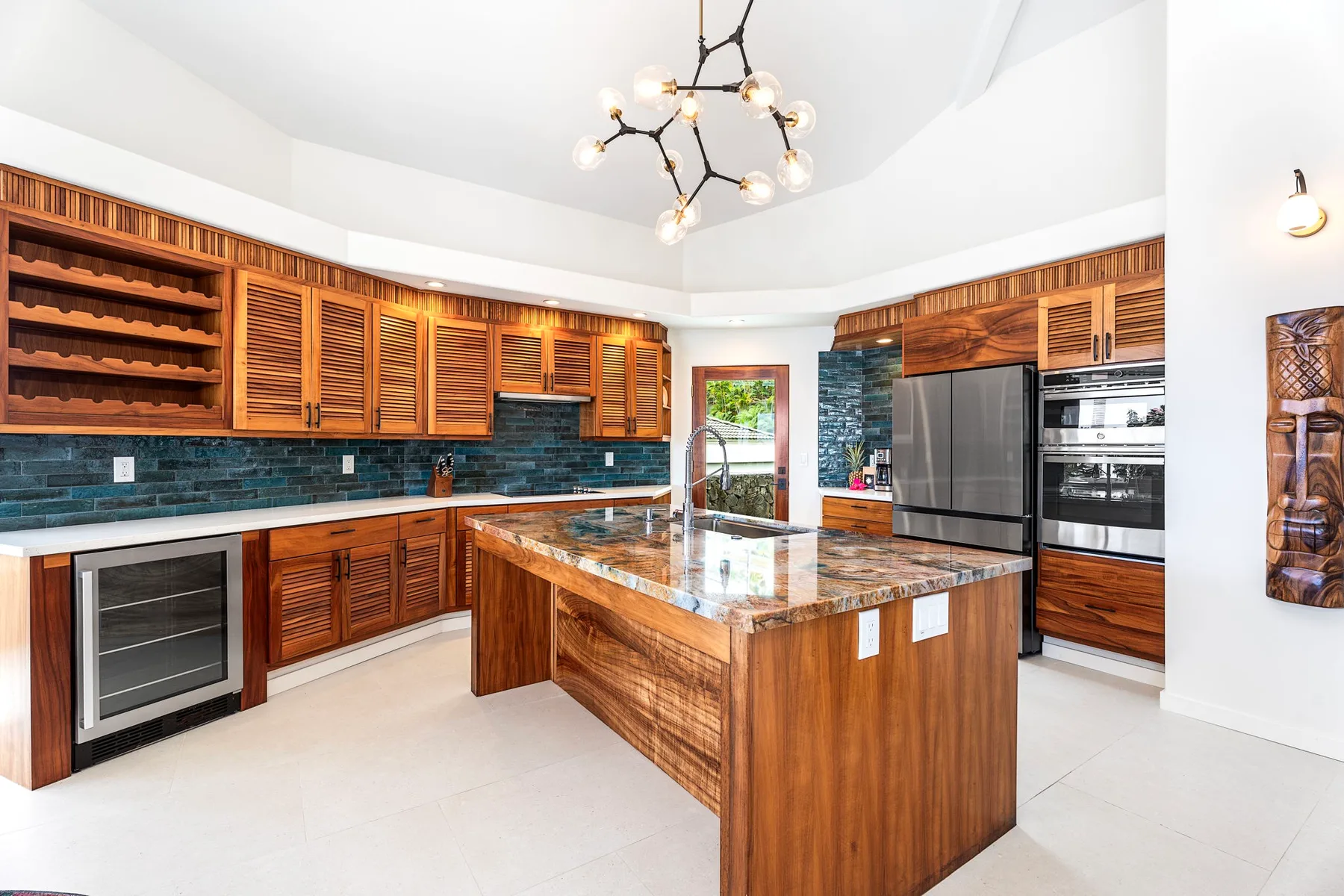 Una cocina amplia con gabinetes de madera, salpicadero de azulejos oscuros e isla central.
