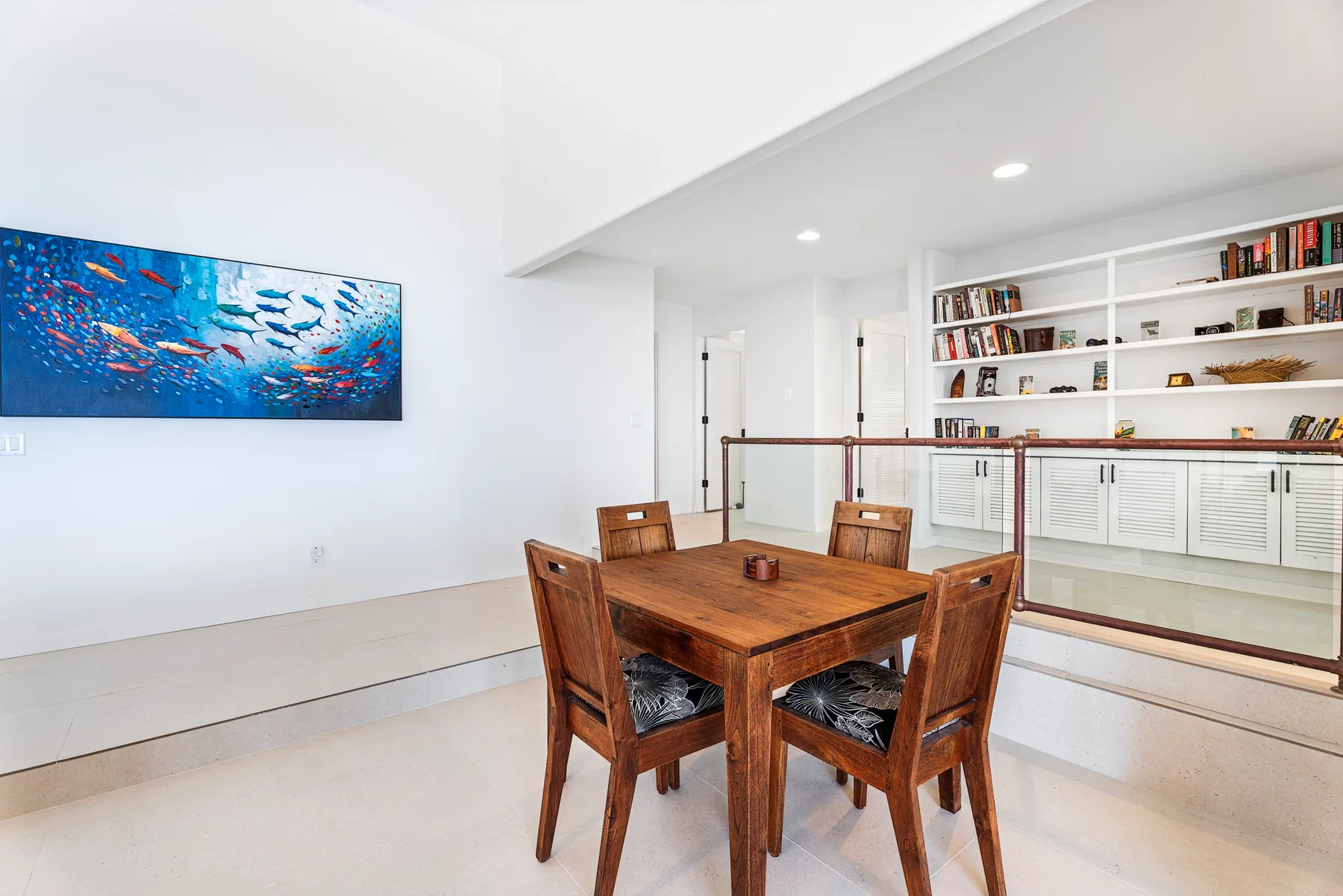 Un comedor con una mesa de madera y estanterías empotradas en la pared del fondo.