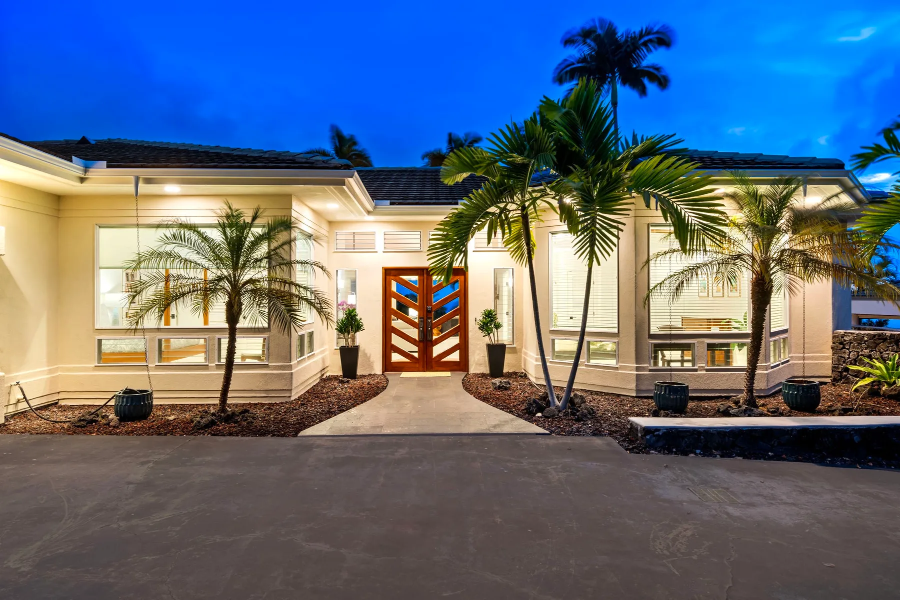Una casa grande con una entrada decorativa y palmeras al frente.