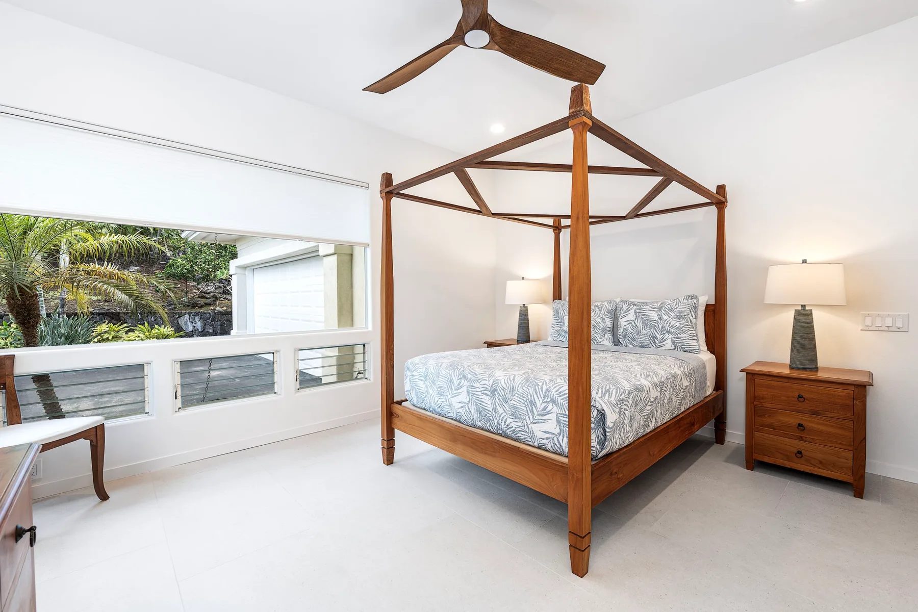 Un dormitorio luminoso con una cama con dosel de madera y ventanas amplias.