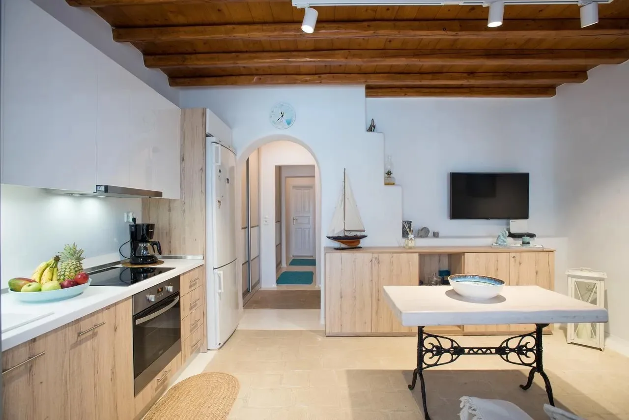 Una luminosa cocina y comedor de apartamento con techo de madera y mesa isla.