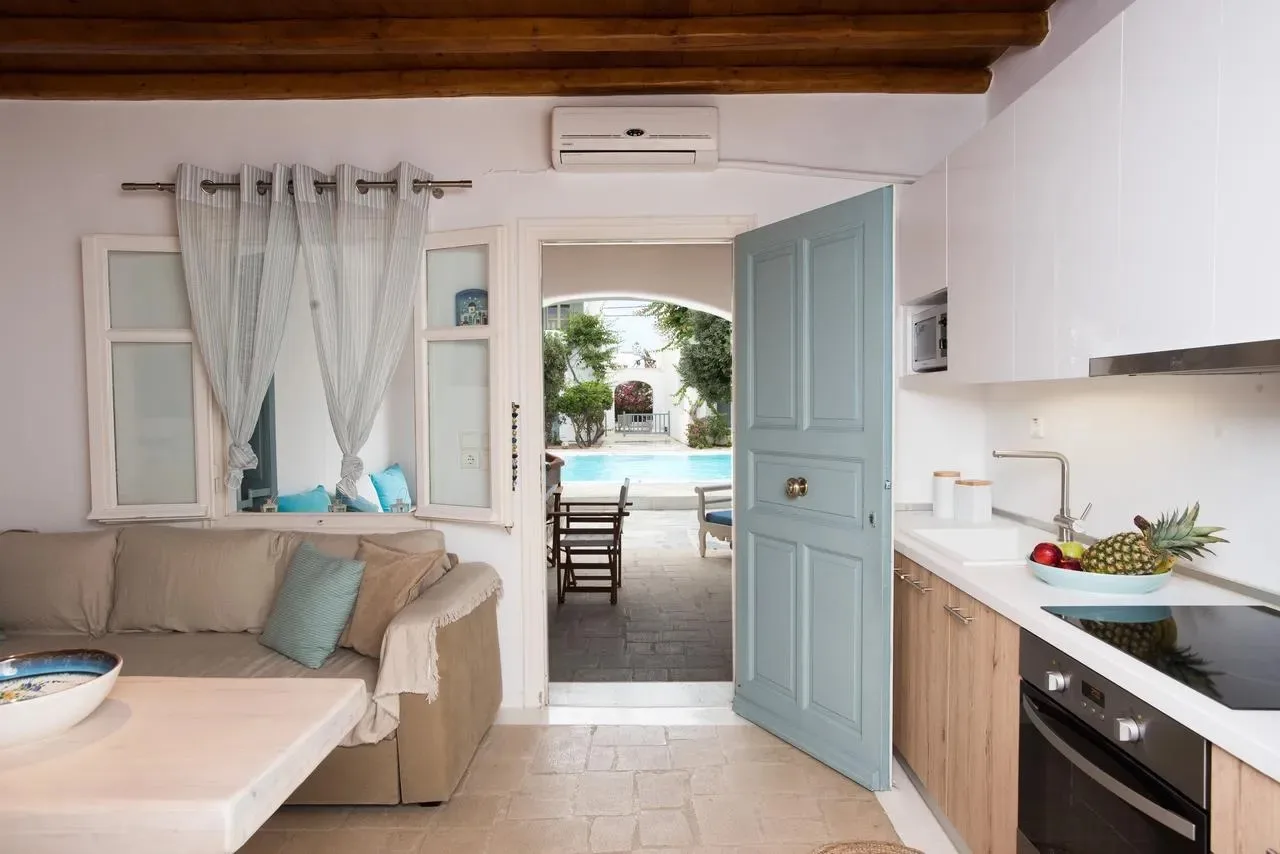 Una sala luminosa y una pequeña cocina dan a un patio con piscina.