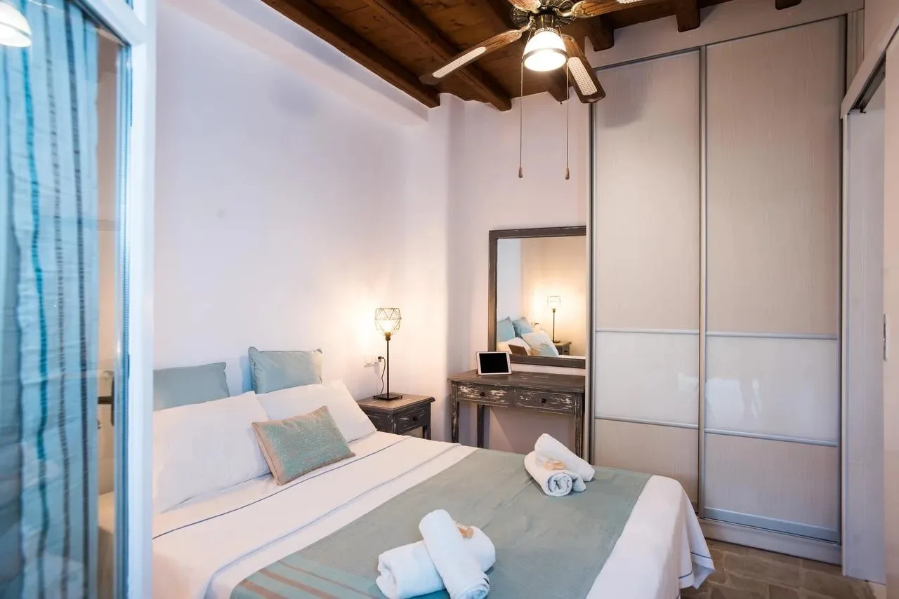 Un dormitorio con una cama bien hecha y puertas correderas de armario.
