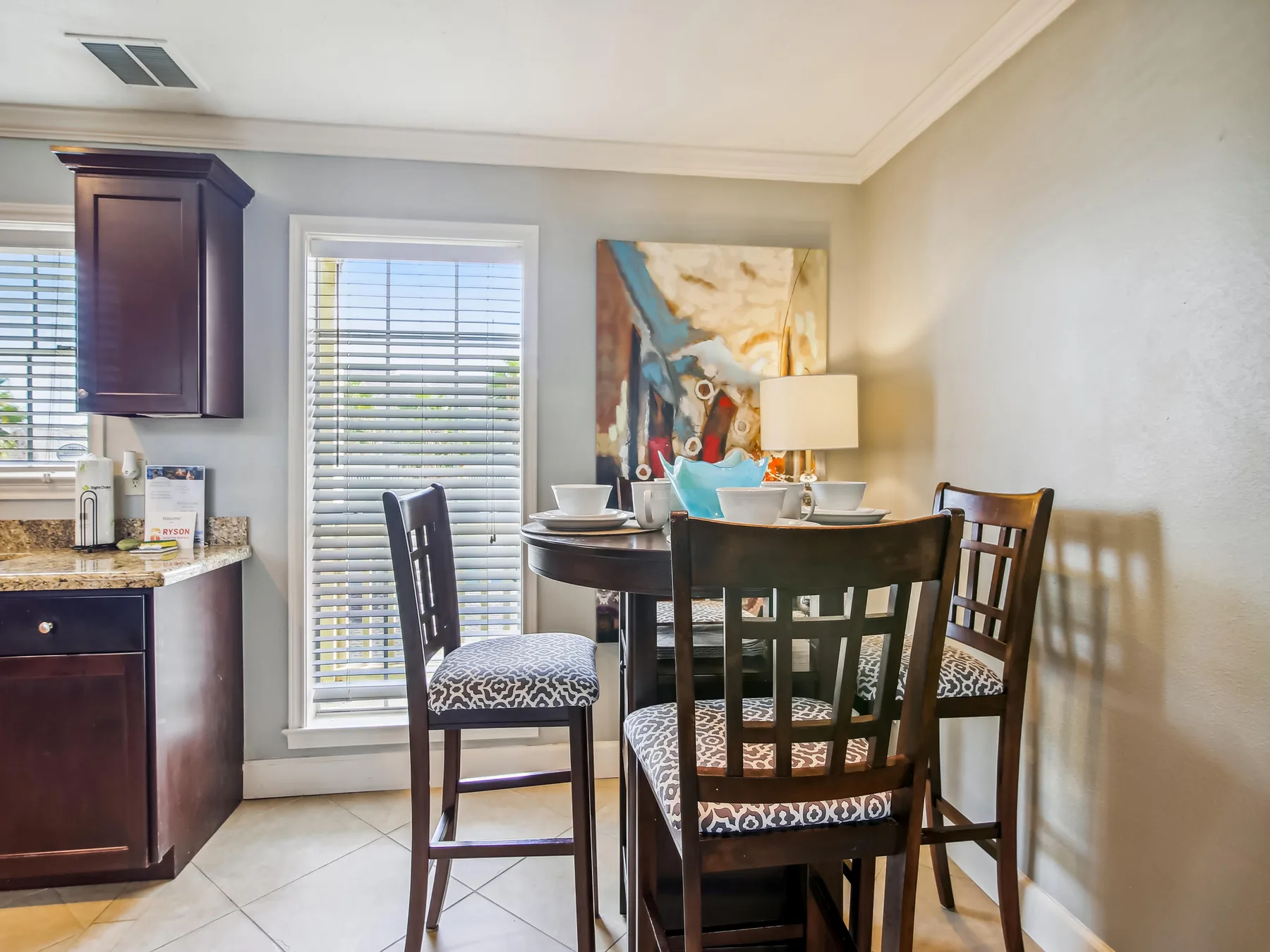 A dining area with a dark table and chairs beside a kitchen counter.