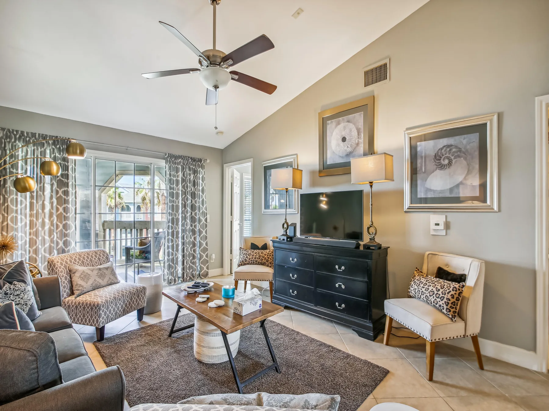 A living room with seating, a television, and a sliding glass door.