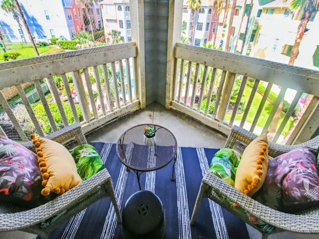Zona de estar en un balcón con una mesa pequeña y vistas a edificios cercanos.