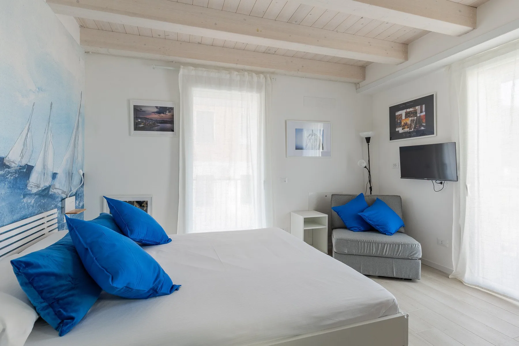 Un dormitorio luminoso con una cama grande y cojines azules.