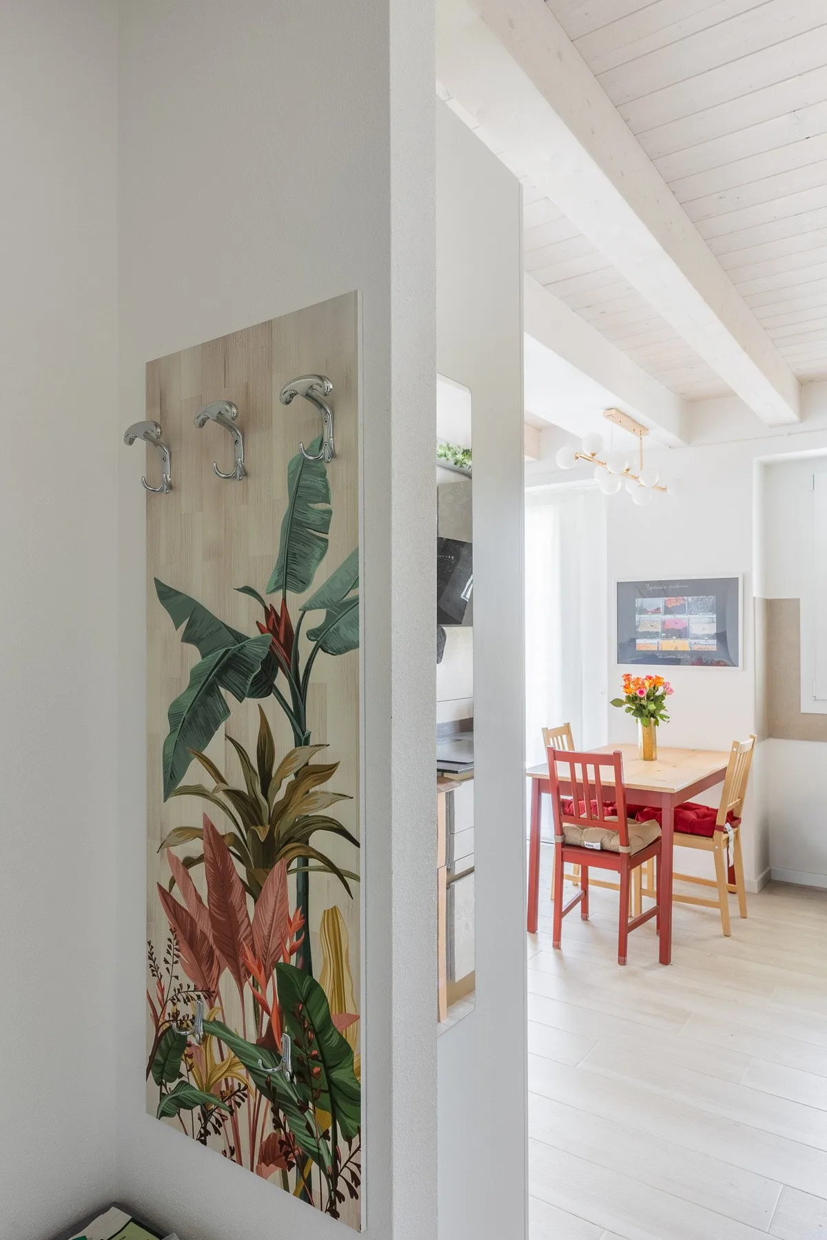 Un comedor luminoso con una mesa de madera y sillas junto a un mural botánico.