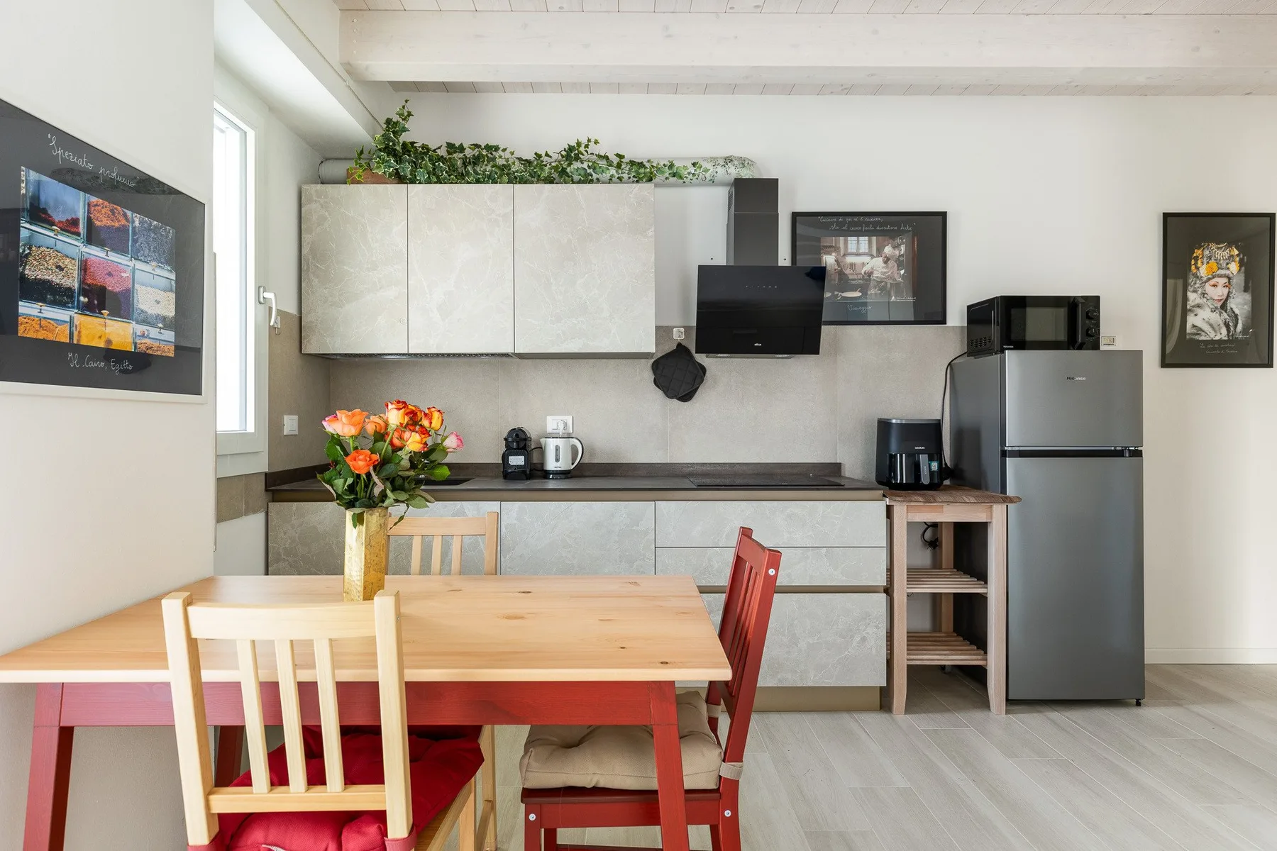 Una cocina y comedor luminosos con una mesa de madera y un refrigerador.