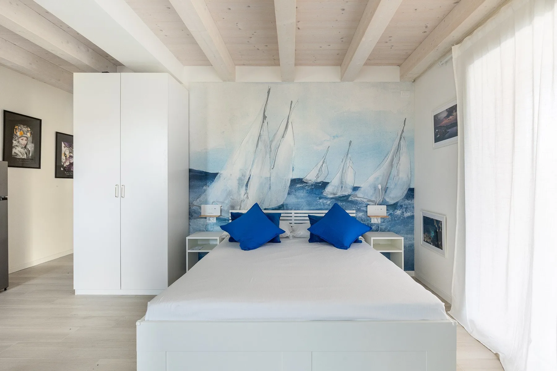 Un dormitorio con una cama frente a un mural de veleros en el mar.