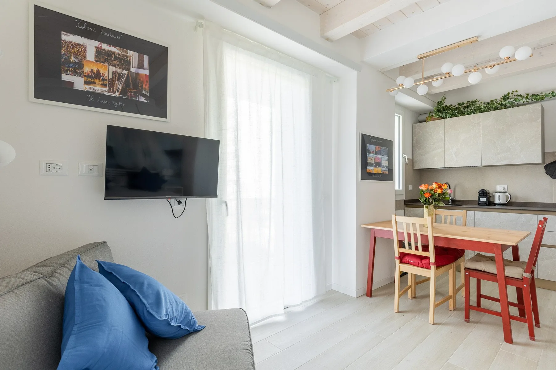 Una luminosa sala de estar y comedor con sofá, mesa y armarios de cocina.