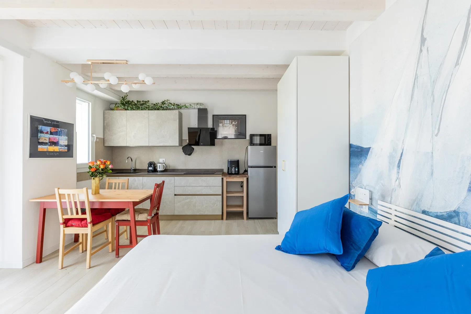 Un estudio luminoso tiene una cama junto a un comedor y una cocina compacta.