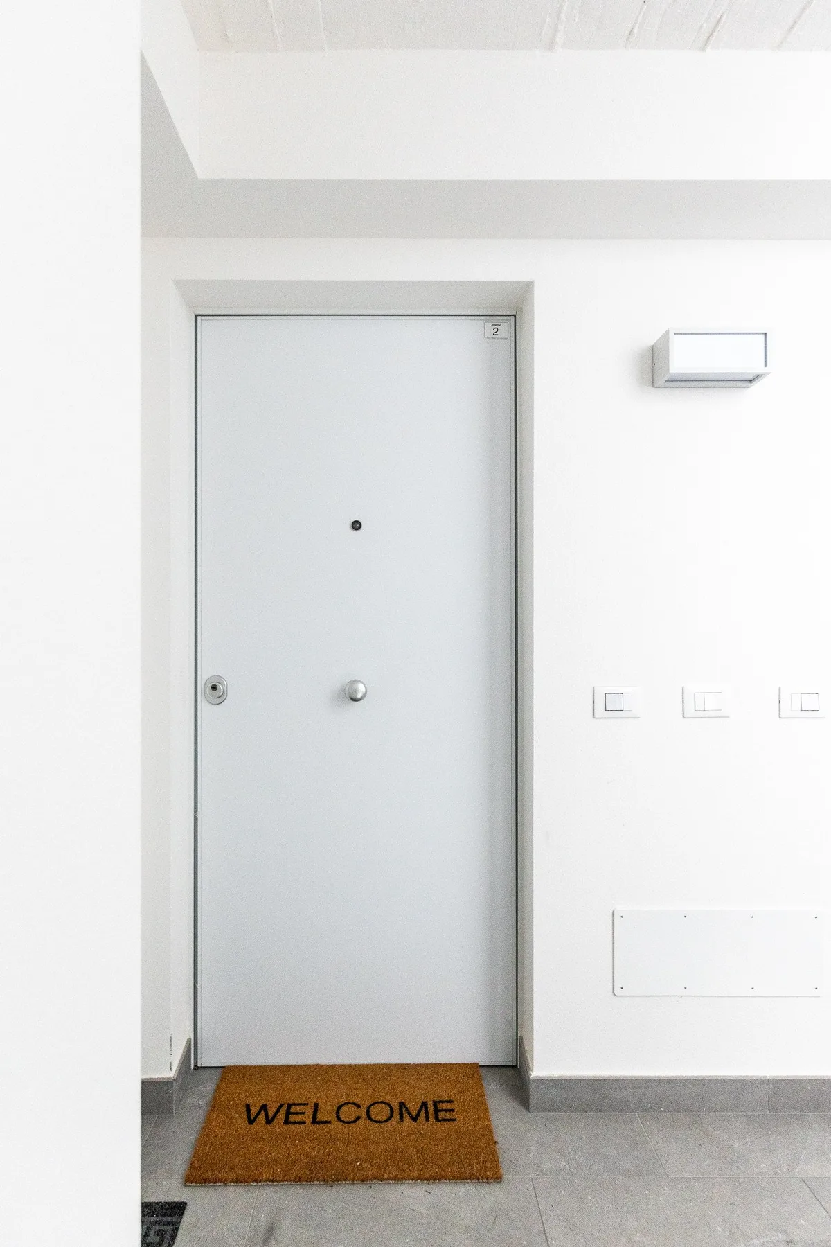 Una entrada luminosa con una puerta cerrada y un felpudo de bienvenida.